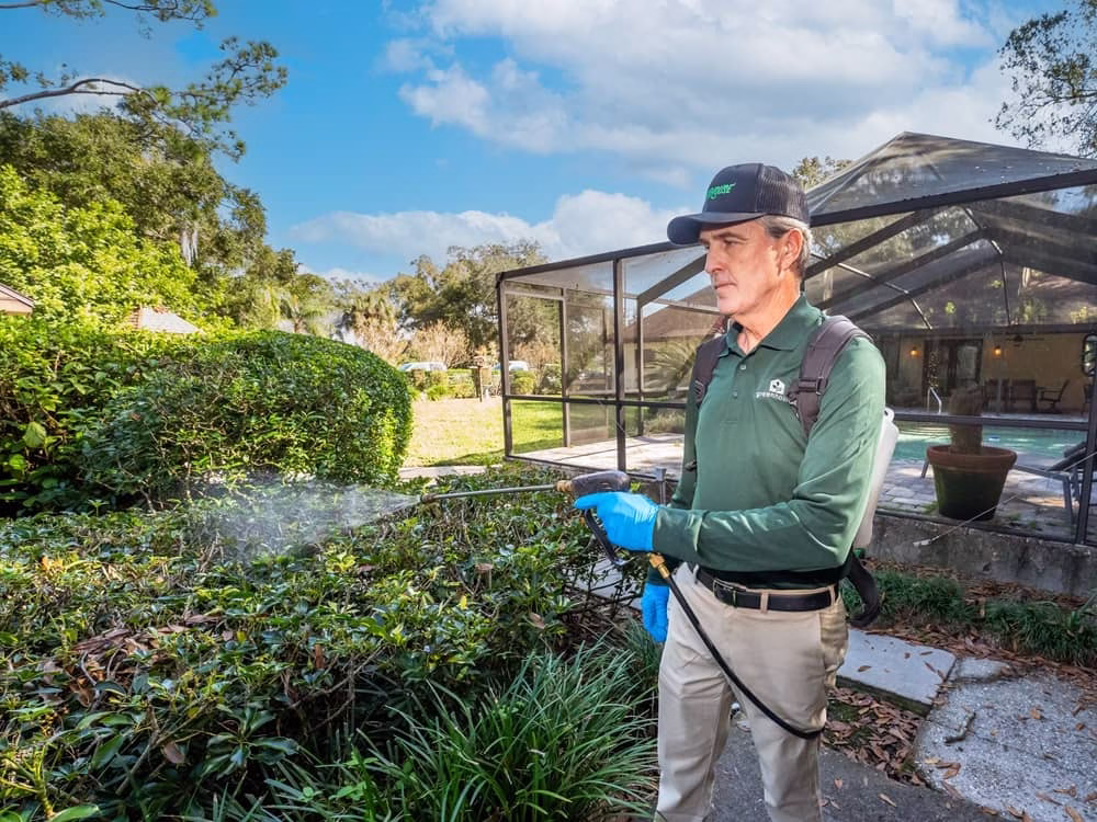 Man spraying in bushes with pipe